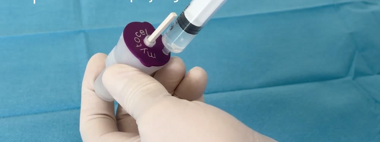 Gloved hands drawing the prepared suspension from the cartridge into a syringe